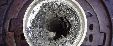 Flow assurance picture 1 hole in a bucket of dried concrete on top of circular rusted metal