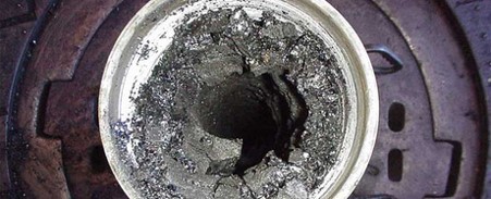 hole in a bucket of dried concrete on top of circular rusted metal