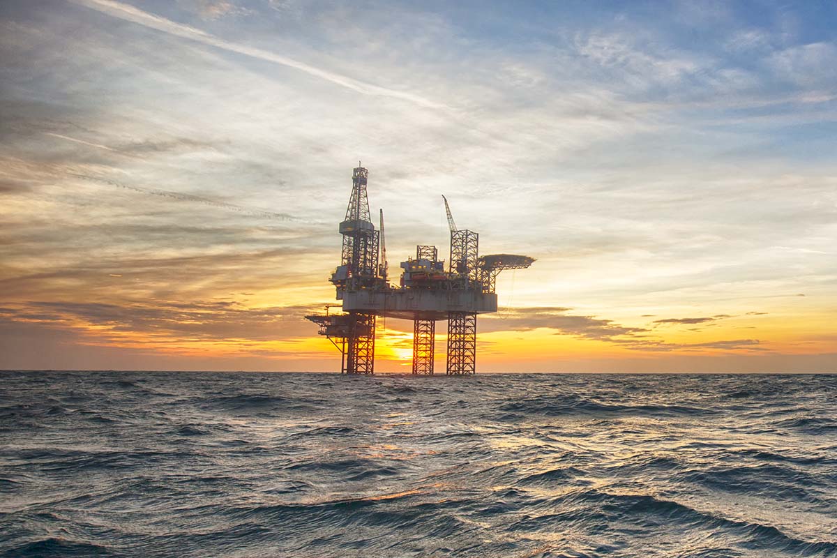 image of an oil rig in the ocean during sunrise